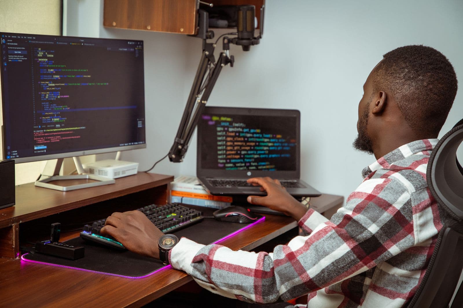 Developer writing code across a desktop and laptop